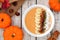 Autumn pumpkin smoothie bowl, scene on white wood