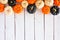 Autumn pumpkin top border in Halloween colors orange, black and white against a white wood background