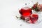 Autumn red herbal tea in transparent teapot, cup with dry leaves, rose hip, hawthorn berries in sunlight on white wood table, copy