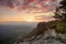 Autumn rocky landscape within sunset. Colorful sky above deep misty valley full of evening humidity. Sun on horizon.