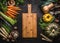 Autumn seasonal food background with colorful various pumpkins and organic farm vegetables around wooden cutting board, top view.