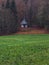 Autumn September landscape wooden cabin on forest edge scenic view with green grass meadow and brown falling leaves country side