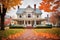 autumn setting of colonial home with dual chimneys and fallen leaves