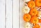 Autumn side border of orange and white pumpkins and berries on a white wood background