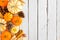 Autumn side border of pumpkins and fall decor over a rustic white wood background