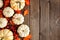 Autumn side border of white pumpkins and red fall leaves on a rustic wood background