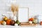 Autumn still life. Picture frame template, harvest of pumpkins, dry wheat on white table in scandinavian kitchen interior. Autumn