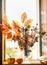 Autumn still life on window sill with branch with brown, yellow and orange leaves in glass vase and pumpkins at background with