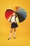 Autumn style. Small girl holding colorful umbrella for autumn weather on yellow background. Little schoolchild going to