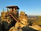 Autumn sunny morning scene. Wooden cabin on main peak of rock as view point, dark sky, autumn mist in valley.