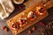 Autumn sweet potato crostini appetizers with cheese, cranberries and pecans above on rustic wood