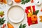 Autumn table setting. White plate, golden cutlery and fall decorations.