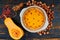 Autumn tart with goji berry in the baking dish decorated with hazelnuts and cinnamon on the black wooden background