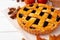 Autumn thankgiving pie on white wooden board decorated with dry leaves and cinnamon sticks