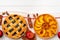 Autumn thankgiving pies on white wooden board decorated with dry leaves and cinnamon sticks