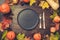 Autumn and Thanksgiving day table setting with fallen leaves, pumpkins, spices, empty black platter and vintage cutlery on brown w