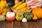 Autumn Thanksgiving motive with a basket full with corn cobs and different colorful pumpkins on an old rustic wooden background