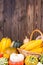 Autumn Thanksgiving motive with a basket full with corn cobs and different colorful pumpkins on an old rustic wooden background