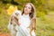 Autumn Time with pets. Woman with doggy on fall maple leaf outdoors. Emotional support.