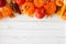 Autumn top border of leaves, pumpkins, apples and fall decor on a white wood background