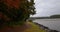 Autumn trail by the lake at windy day with fallen leaves swirling around