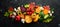 Autumn vegetables and fruits on a black stone background: Pumpkin, tomatoes, corn, pomegranate, persimmon, apple.
