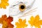 Autumn vibe composition. Blank greeting card mockup. PErfume jar, colorful maple leaves. White table background. Flat