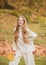 Autumn vogue. Young stylish hipster girl wearing modern dress in urban park smiling happy. Caucasian female model. Fall