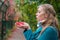 Autumn and a walk in the fresh air. A young blonde holds red leaves in her hands and blows them away. The view of the profile.