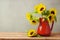 Autumn wallpaper. Sunflowers in red vase on wooden table