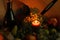 Autumn warm scene. Stll life harvest. Thanksgiving post card greetings. Candle flame with ripe fruits and bottle of wine