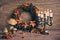 Autumn wreath and still life with ancient candelabrum candle stick , candles with flame. Wooden mushrooms and berries on wood.