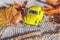 Autumnal Background. Yelllow toy car and dried orange fall maple leaves on grey knitted sweater. Thanksgiving banner copy space.