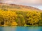 Autumnal landscape with colorful trees, sandstone rock formations and water surface.