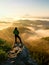 Autumnal misty morning in nature. Hiker in black stand on peak in rock