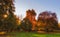 Autumnal park view with colorful foliage,blue sky,sun shining through trees