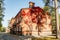 Autumnal view of red brick building covered by red foliage of parthenocissus