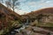 An autumnal waterfall and stone packhorse bridge at Three Shires