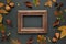 Autumnal-winter composition with vintage frame, dried leaves, bark of trees and berries on dark background.  Flat lay, copy space