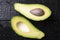 Avacado and seed on black wooden table, top view