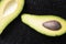 Avacado and seed on black wooden table, top view and copy space