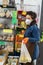 Avetrana, Italy, - Marth 16, 2020. An Italian greengrocer is serving a bag with apples, wearing medical mask and gloves respecting