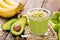 Avocado and banana smoothie with oats with ingredients in glass jar on wooden background