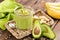 Avocado and banana smoothie with oats with ingredients in glass jar on wooden background