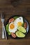 Avocado breakfast, fried eggs with whole grain toast bread on wooden background. Vertical image, top view