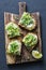 Avocado, cream cheese sandwich with micro greens on a rustic cutting board, top view. Good fats healthy eating concept. Delicious