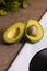 Avocado cut in half ready to eat on table with black long play disk in a corner
