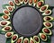 Avocado frame around empty black plate. Copy space food background. avocado half and avocado tree leaves. Top view