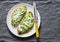 Avocado, goat cheese, grilled ciabatta sandwiches on grey background, top view