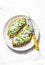 Avocado, goat cheese, grilled ciabatta sandwiches on light background, top view